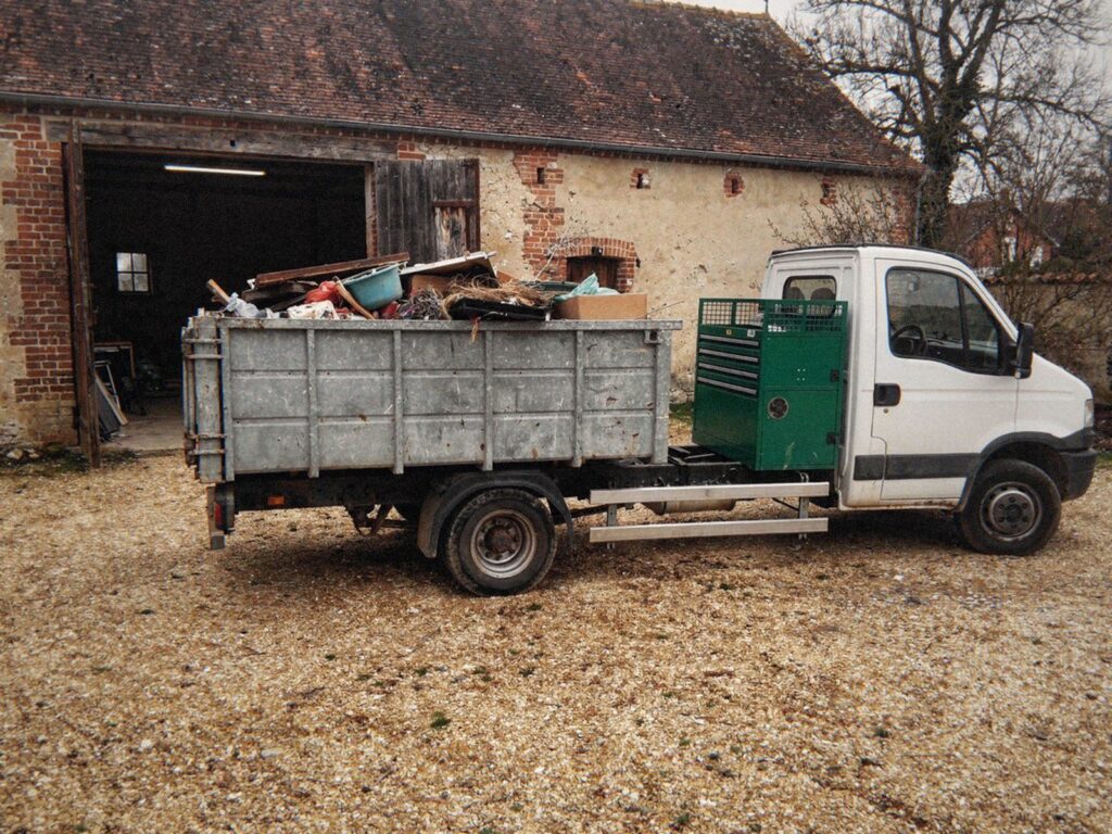 Camion de MJ Débarras chargé dans la cour d'une ancienne ferme de la Dombes pendant le débarras d'une grange
