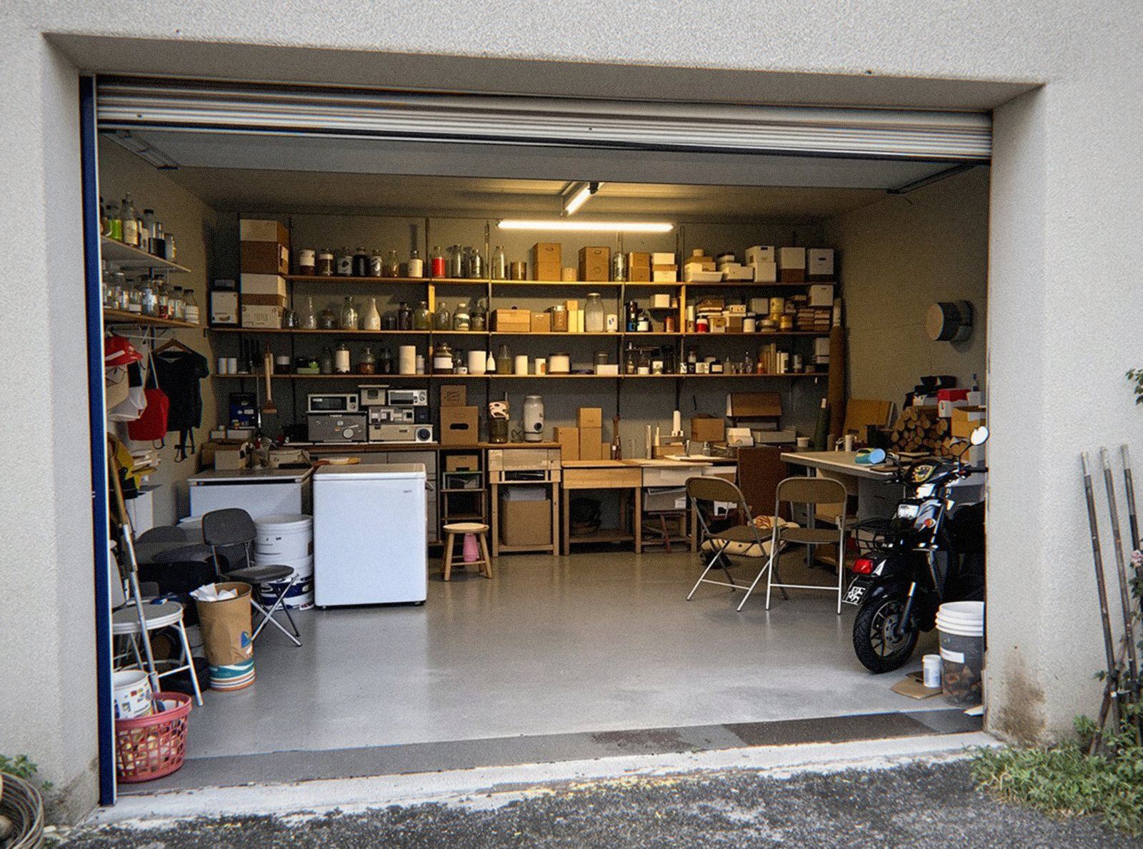 Garage en sous-sol plein d'étagères, d'un congélateur et de cartons avant un débarras de maison à Miribel