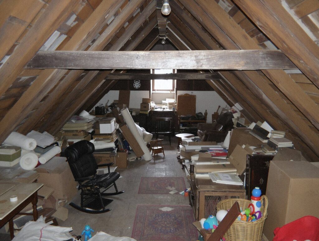 Grenier sous charpente d'une maison de l'Ain rempli de cartons, de fauteuils et de jouets à débarrasser