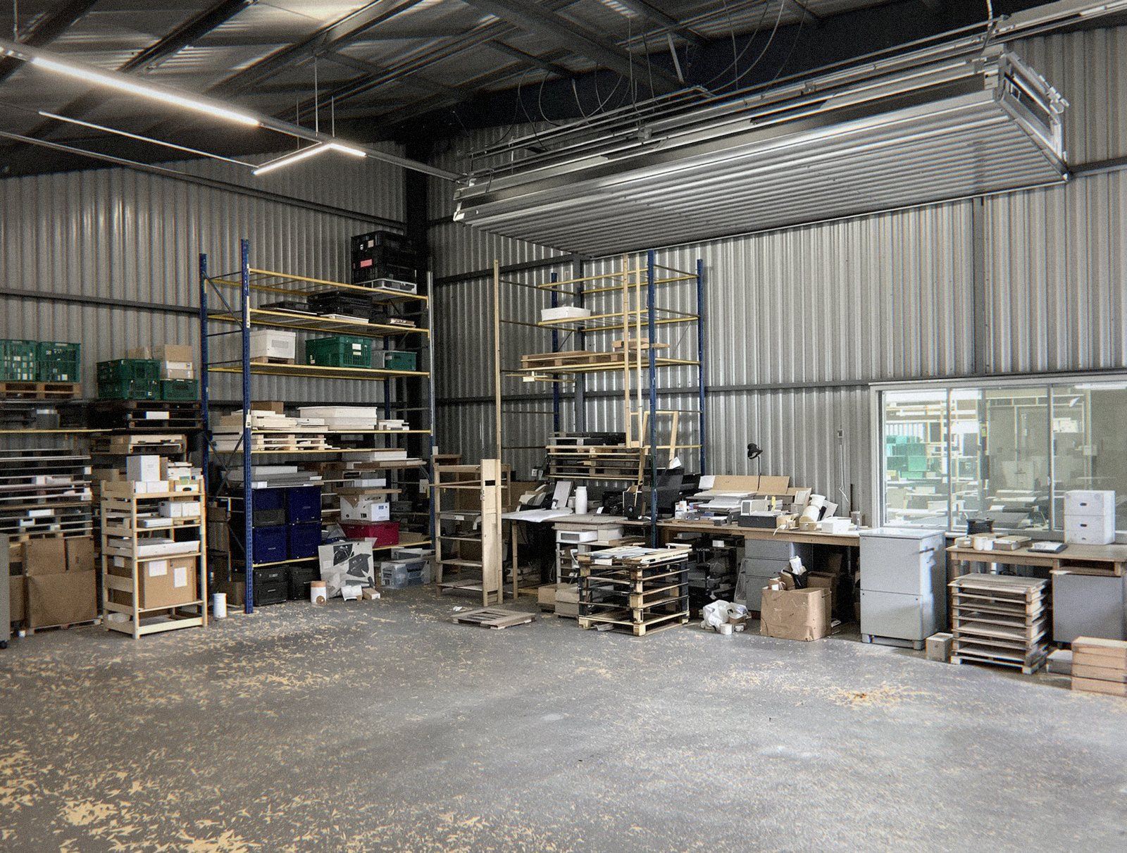 Atelier d'une zone d'activité de l'Ain rempli de racks, de palettes et de mobilier avant son débarras